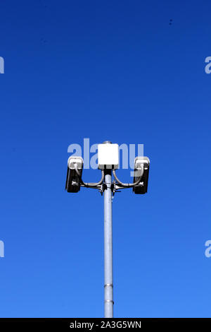 Vista verticale delle telecamere di sicurezza sul palo alto contro il profondo blu del cielo Foto Stock