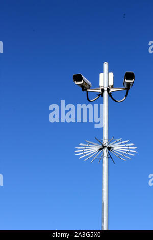 Vista verticale delle telecamere di sicurezza sul palo alto contro il profondo blu del cielo Foto Stock