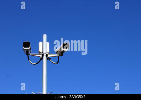 Vista del paesaggio di telecamere di sicurezza sul palo alto contro il profondo blu del cielo Foto Stock