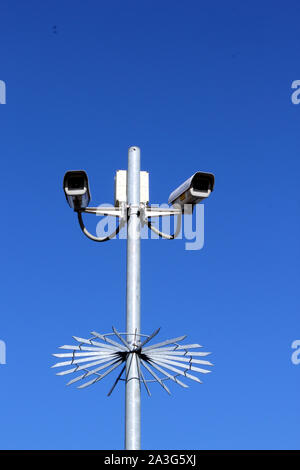 Vista verticale delle telecamere di sicurezza sul palo alto contro il profondo blu del cielo Foto Stock