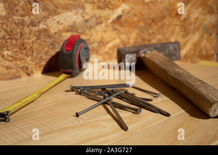 Martello chiodi e nastro di misurazione sul tavolo di legno Foto Stock