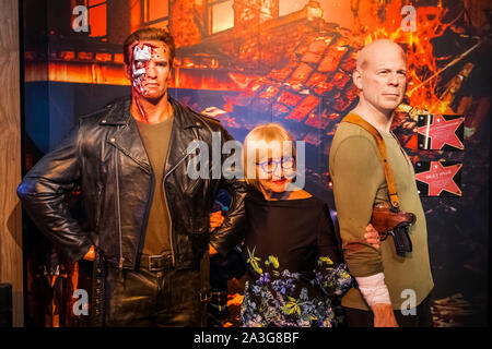 Inghilterra, Londra, Marylebone, vista interna della signora Tussauds, turistico in posa con Waxwork figure di Arnold Schwarzenegger e Bruce Willis Foto Stock