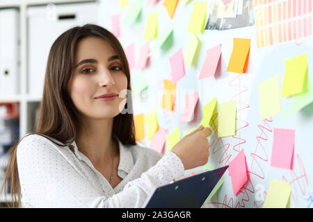 Bellissima femmina clerk abbattendo adesivo di carta cercando nella fotocamera Foto Stock