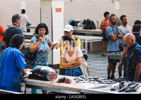 Funchal, Madeira, Portogallo - Sep 21, 2019: Donna l'acquisto di pesce da un venditore di un tradizionale mercato del pesce Mercado dos Lavradores. Il mercato coperto posto con pesce fresco. Di Tonno. L'abuso di animali, diritti, crudeltà. Foto Stock