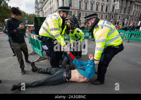 La polizia rimuovere un dimostratore durante una ribellione di estinzione (XR) protesta in Westminster, Londra. Foto Stock