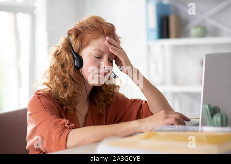 Curly donna tocca la fronte mentre un senso di vertigine Foto Stock