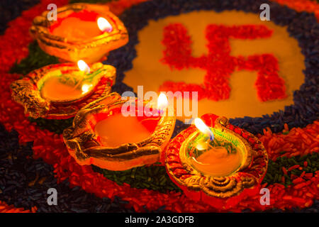 Indian Festival Diwali, Diya lampade a olio accesa sulla colorata rangoli con la svastica simbolo. Tradizionale indù. Felice Deepavali. Foto Stock