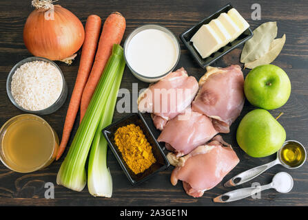 Pollo zuppa Mulligatawny Ingredienti: cosce di pollo e verdure, il curry in polvere e di altri ingredienti sul fondo in legno Foto Stock