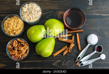 Acero cotto cannella Pera Ingredienti: D'anjou pere, fiocchi d'avena e altri ingredienti al buio su un sfondo di legno Foto Stock