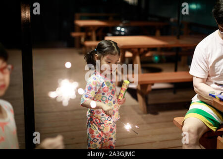 Bambino tiene in mano un Sparkler su sfondo scuro Foto Stock