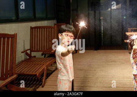 Bambino tiene in mano un Sparkler su sfondo scuro Foto Stock