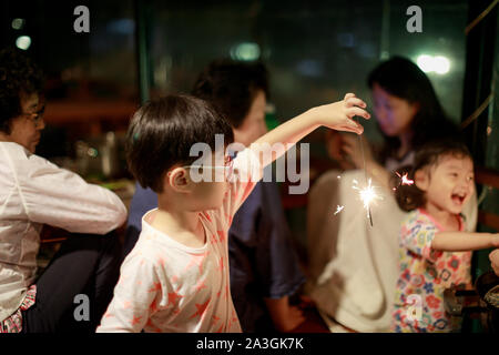 Bambino tiene in mano un Sparkler su sfondo scuro Foto Stock