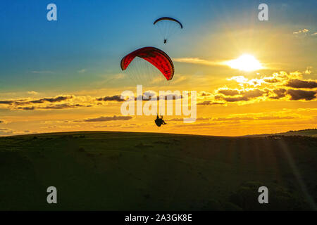 Un parapendio paraglides oltre il South Downs National Park durante il tramonto. Regno Unito Foto Stock