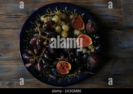 Appena raccolto frutti d'autunno. Bianco e nero uva e fichi scuro su un tavolo di legno. Foto Stock