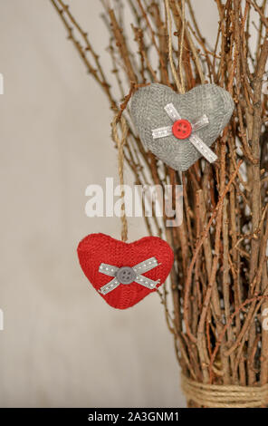 Due cuori a maglia appeso su un ramo. Simbolo di amore e di San Valentino celebratione. Tonica foto. Foto Stock