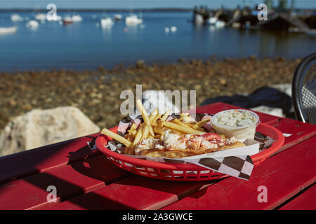 Mangiare tradizionale Maine lobster roll con coleslaw e patatine fritte su un lungomare porto nel Maine. Foto Stock