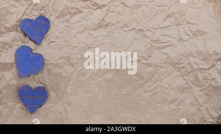 Fatto a mano Jeans cuori su un accartocciata craft lo sfondo della carta. Appartamento laico, vista dall'alto, stile minimal, copia spazio per il testo. Simbolo di amore, per San Valentino d Foto Stock
