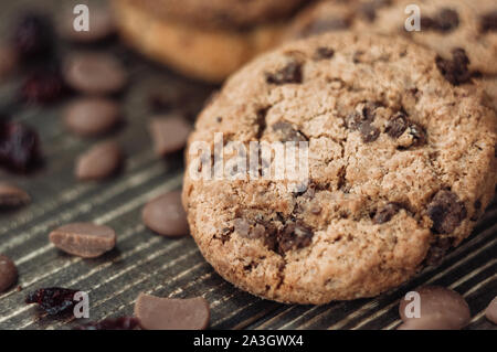 Una pila di fiocchi d'avena i biscotti con pezzetti di cioccolato e frutta candita giace su di un tavolo di legno. Tavolo rustico. Tonificazione vintage. Integratore utile i cookie Foto Stock