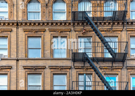 Giallo facciata in mattoni e una coppia di scarponi appese delle scale antincendio. Chelsea, New York.