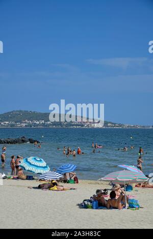 Francia, Herault, Meze, vacanzieri su una spiaggia di La laguna di Thau con il Mont Saint Clair in background Foto Stock