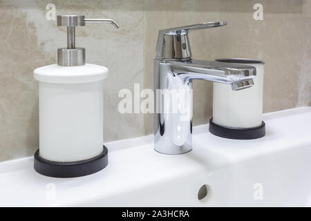 Il sapone e lo shampoo dispenser vicino ceramica rubinetto acqua lavandino con rubinetto in costosi loft bagno Foto Stock