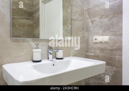 Il sapone e lo shampoo dispenser vicino ceramica rubinetto acqua lavandino con rubinetto in costosi loft bagno Foto Stock