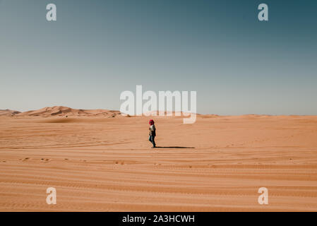 Uomo in turbante camminare da solo nel deserto del Sahara Foto Stock