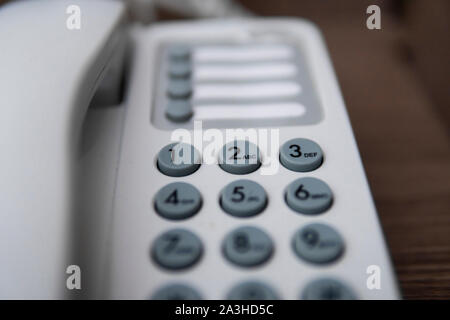 Vintage bianco telefono con battoms grigio su un tavolo marrone in hotel. Foto Stock