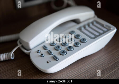 Vintage bianco telefono con battoms grigio su un tavolo marrone in hotel. Foto Stock