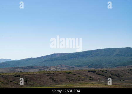 Paesaggio della Crimea. La steppa in primo piano e le montagne coperte di nebbia in background Foto Stock