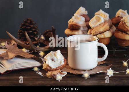 Caldo e fumante tazza di caffè con rotolo cannella e libro aperto il fuoco selettivo sulla bevanda con estrema sfocato in primo piano e sullo sfondo. Foto Stock