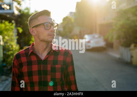 Giovane uomo che indossa rosso a scacchi shirt nelle strade all'aperto Foto Stock