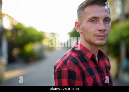 Giovane uomo che indossa rosso a scacchi shirt nelle strade all'aperto Foto Stock