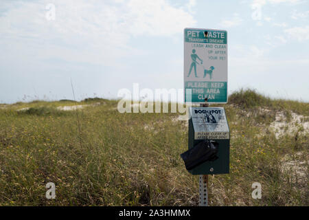 Sacchetto di plastica dispenser e il segno che ricorda il proprietario di pet di pulizia dopo i loro animali a Rosamond Johnson, Jr. Parco Nazionale nei pressi di Pensacola, Florida, Foto Stock