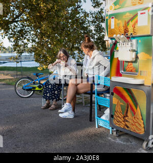 Belgrado, Serbia, Sep 10, 2019: giovane donna gelato venditore, posti a sedere accanto a una morbida crema erogatore al Danubio lungofiume a Zemun Foto Stock
