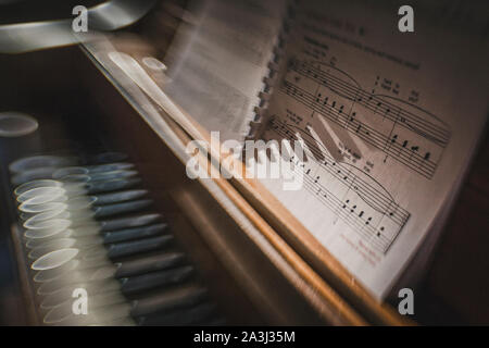 Sole di mattina brilla su tasti di pianoforte con la musica del foglio di Sfocatura creativa Foto Stock