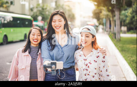 Happy amici asiatici vlogging in città la stazione degli autobus - i giovani alla moda con sospensione cardanica all'aperto dello smartphone Foto Stock