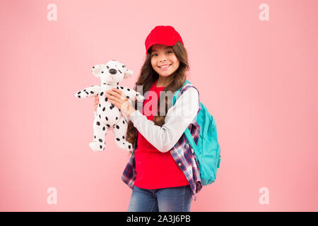 Giocattolo preferito. Felice piccolo bambino tenere giocattolo morbido su sfondo rosa. Bambina in stile hipster sorriso con il cane giocattolo. Giocattolo per bambini negozio o supermercato. Foto Stock