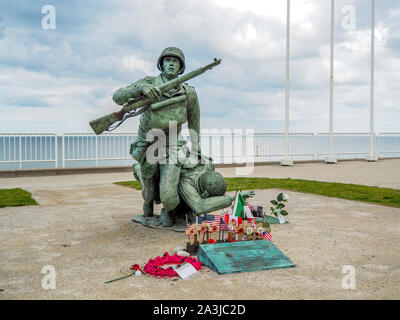 Memorial raffigurante soldato ferito che porta il compagno alla spiaggia di Omaha, in Normandia, Francia, il settantacinquesimo anniversario dell'invasione. Foto Stock