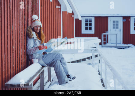 Ragazza turistica si siede vicino rorbu con una mappa a isole Lofoten. Norvegia Foto Stock