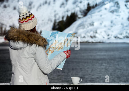 Ragazza turistica si siede vicino rorbu con una mappa a isole Lofoten. Norvegia Foto Stock