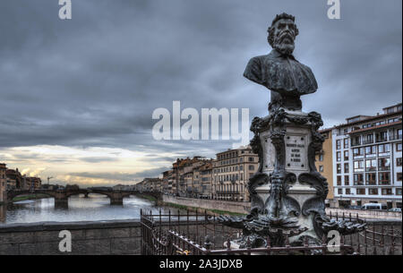 Foto scattata sul Ponte Vecchio, Firenze, mostrando il fiume Arno, ponti e il monumento con il busto di Benvenuto Cellini Foto Stock