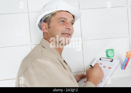 Malinconici uomo builder in elmetto con clipboard Foto Stock