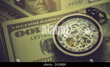 Orologio da tasca e il dollaro di impilamento delle banconote nelle tenebre dello sfondo. Concetto di tempo è denaro o Business. Foto Stock