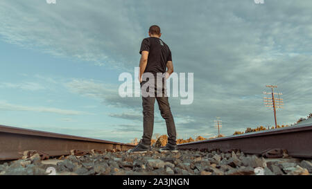 Guy standing sulla ferrovia Foto Stock