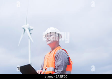 I vecchi ingegnere energetico nella parte anteriore di una turbina eolica Foto Stock