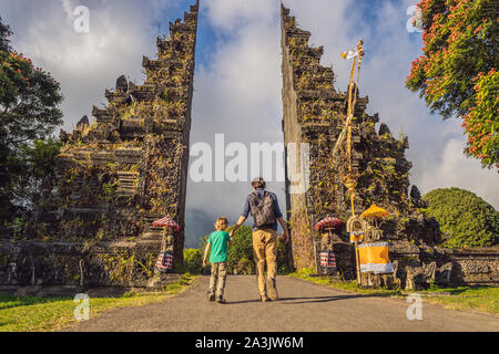 Padre e figlio a piedi attraverso Balinese tradizionale gate indù Candi Bentar vicino a Bedugul, Bratan lago isola di Bali Indonesia. Vacanze a Bali Foto Stock