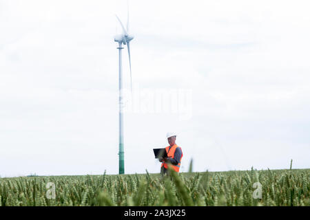 I vecchi ingegnere energetico nella parte anteriore di una turbina eolica Foto Stock