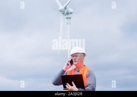 I vecchi ingegnere energetico nella parte anteriore di una turbina eolica Foto Stock