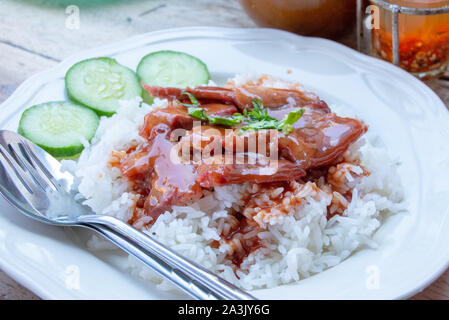 Rosso di maiale con riso e cetrioli su una piastra. Foto Stock